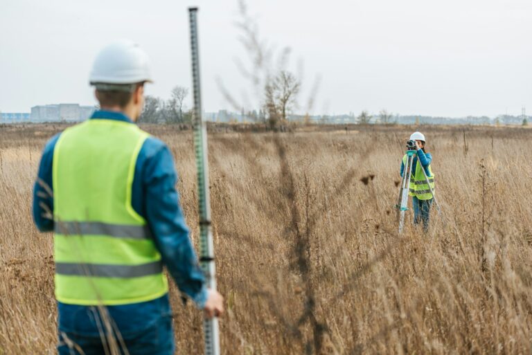 Selective focus of surveyors measuring land with digital level and ruler in field