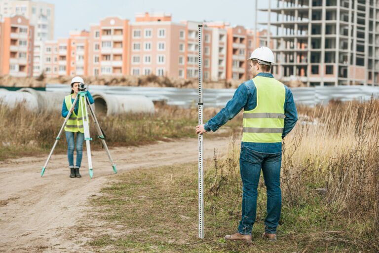 Surveyors measuring land with digital level and ruler