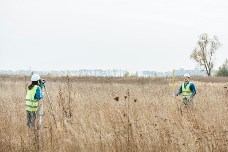 Surveyors measuring land with digital level and ruler in field